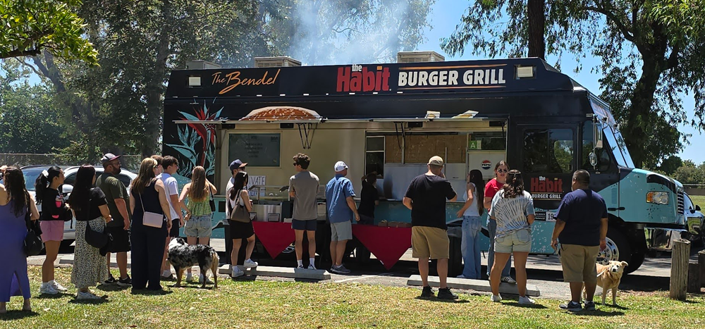 Attendees line up at The Habit Burger Grill food truck during the ISYS Summer Picnic at Tri City Park.