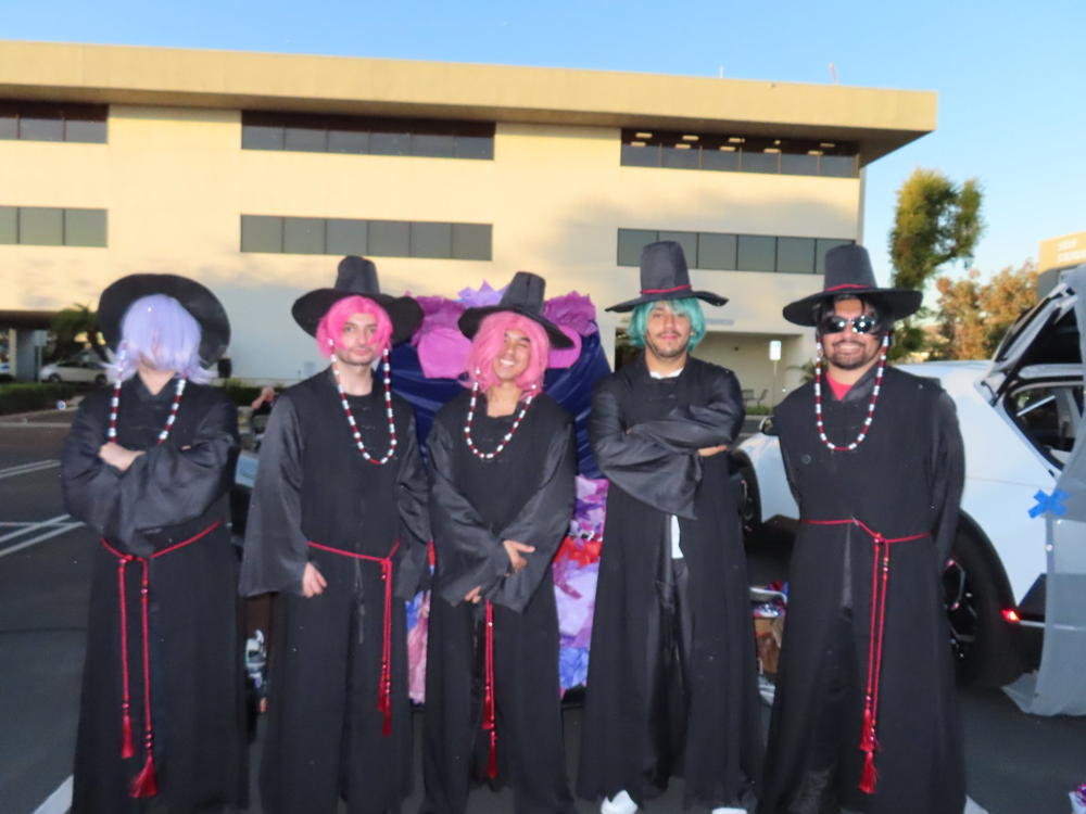 Third-place winners “The Saja Boys” at the ISYS Trunk or Treat 2025, posing together in coordinated black robes, tall hats, and colorful wigs.
