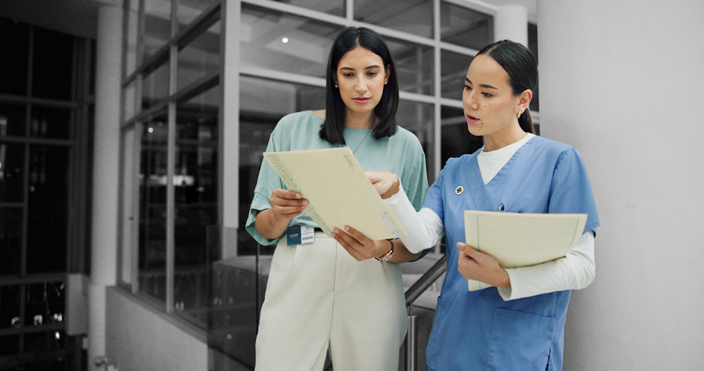 Two healthcare professionals review claim documents together in a clinical office setting, demonstrating collaborative nurse case management.