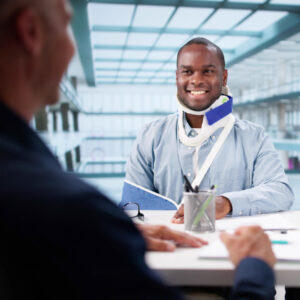Injured worker wearing a neck brace meets with a claims professional to discuss recovery progress and a faster return to work.