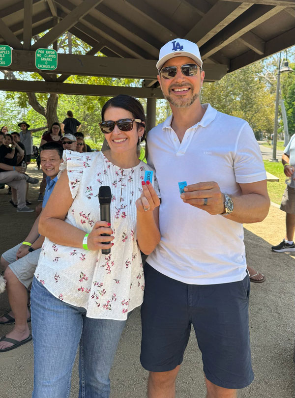 Two attendees display winning tickets during the 50/50 charity raffle at the ISYS® Summer Picnic.