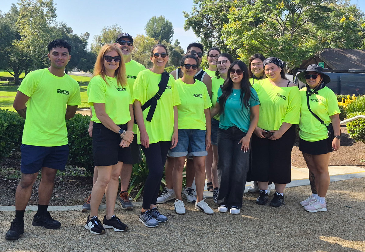 ISYS® Summer Picnic volunteers pose together outdoors in bright volunteer shirts at the 2026 company event.