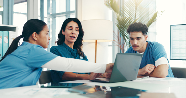 Healthcare professionals reviewing a workers’ compensation treatment plan together on a laptop.
