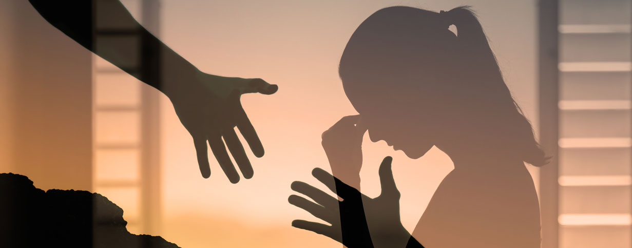 Silhouette of a distressed injured worker receiving support, representing mental health and psychosocial barriers in workers’ compensation recovery.
